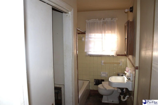 bathroom with a bathing tub, sink, tile walls, and toilet