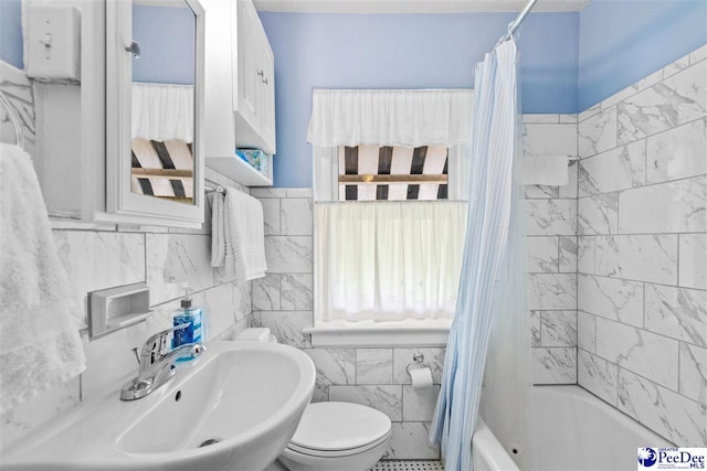 full bathroom with sink, tile walls, shower / bathtub combination with curtain, and toilet