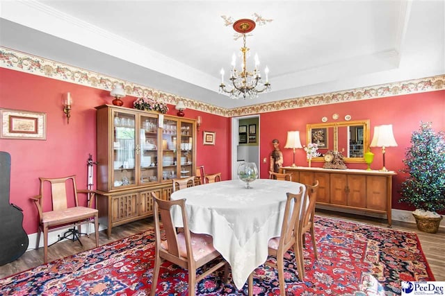 dining room featuring an inviting chandelier, wood-type flooring, crown molding, and a raised ceiling