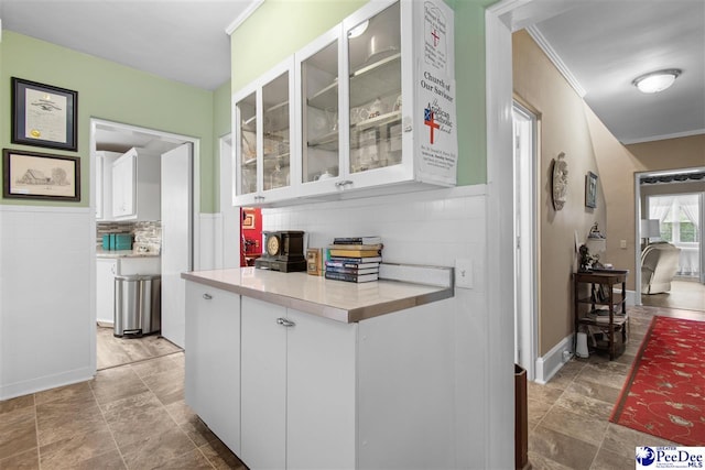 kitchen with backsplash, ornamental molding, and white cabinets