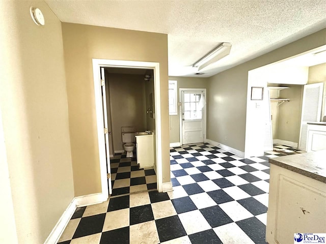 interior space with a textured ceiling, dark floors, and baseboards