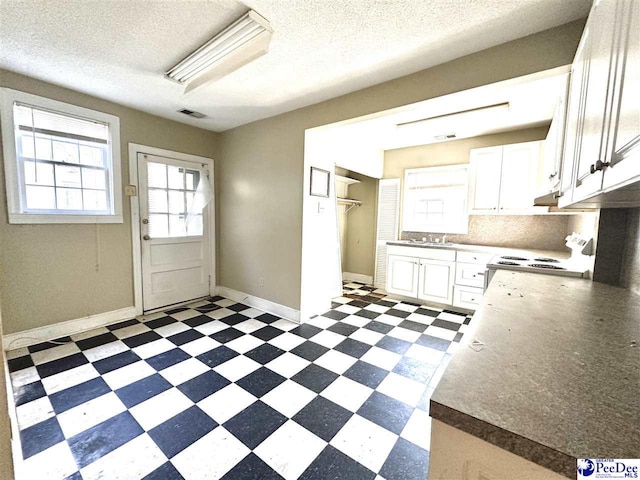 kitchen with dark floors, electric stove, white cabinetry, and dark countertops