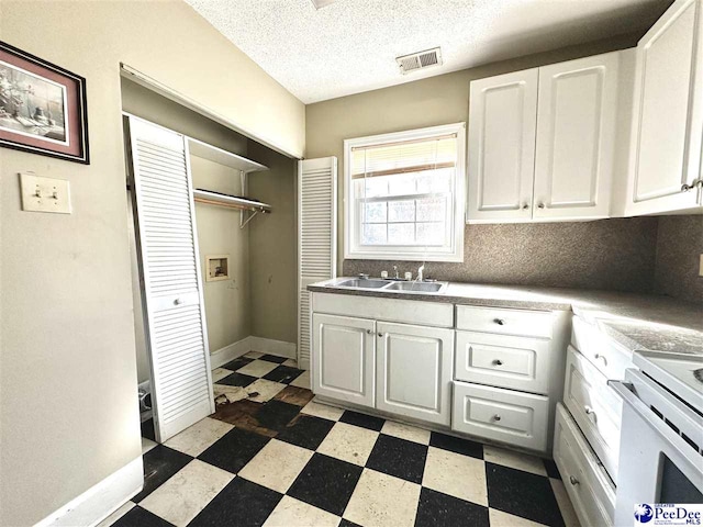 kitchen with dark floors, a sink, visible vents, white cabinets, and light countertops