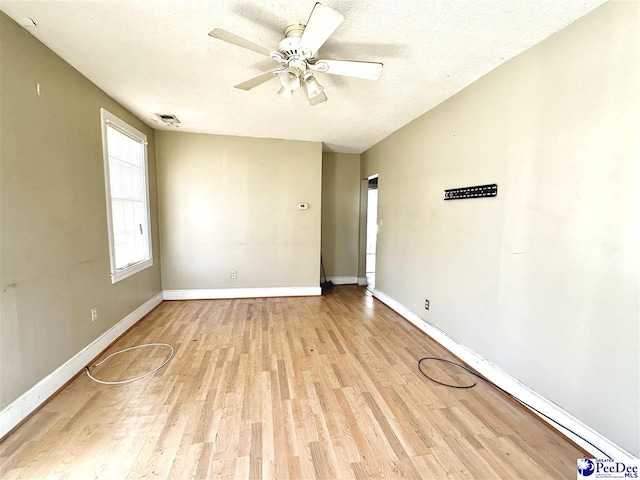 empty room featuring light wood-style floors, ceiling fan, a textured ceiling, and baseboards