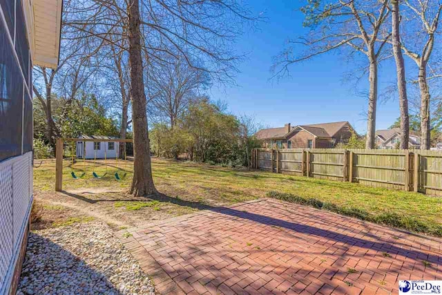 view of yard with a patio area, a fenced backyard, and an outbuilding