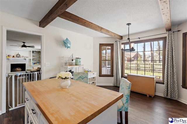 dining room with dark wood finished floors, a textured ceiling, and beamed ceiling