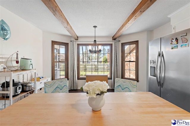 dining space featuring a notable chandelier, a textured ceiling, and beamed ceiling