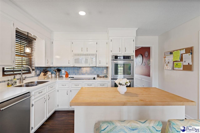 kitchen featuring stainless steel appliances, tasteful backsplash, a sink, and white cabinets