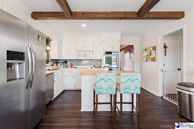 kitchen featuring stainless steel appliances, light countertops, beamed ceiling, and backsplash