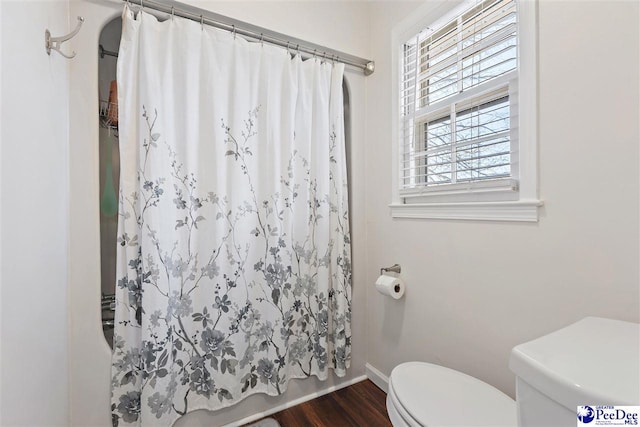 full bathroom with baseboards, toilet, and wood finished floors