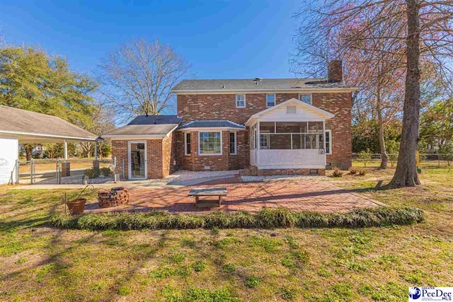 rear view of property with a sunroom, brick siding, fence, and a lawn