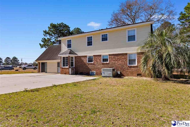 view of front of home featuring a front yard, concrete driveway, brick siding, and central air condition unit