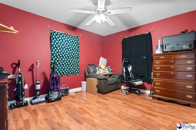 home office with a ceiling fan, a textured ceiling, baseboards, and wood finished floors