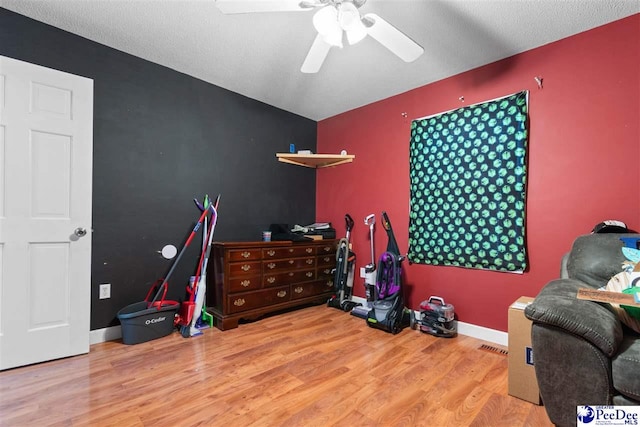 interior space featuring an accent wall, wood finished floors, a ceiling fan, and baseboards