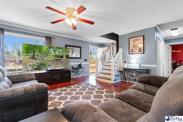 living area featuring a textured ceiling, wood finished floors, a ceiling fan, ornamental molding, and stairway