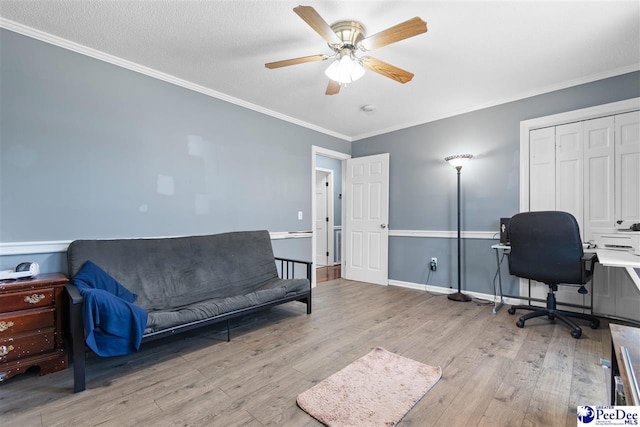 home office featuring light wood-style floors, crown molding, and a ceiling fan