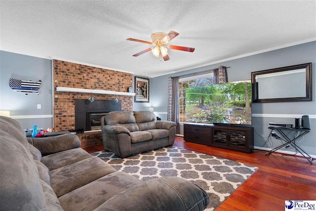 living area featuring ornamental molding, a fireplace, a textured ceiling, and wood finished floors