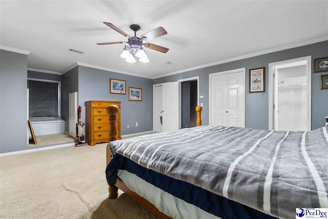 bedroom with visible vents, baseboards, ornamental molding, carpet, and multiple closets