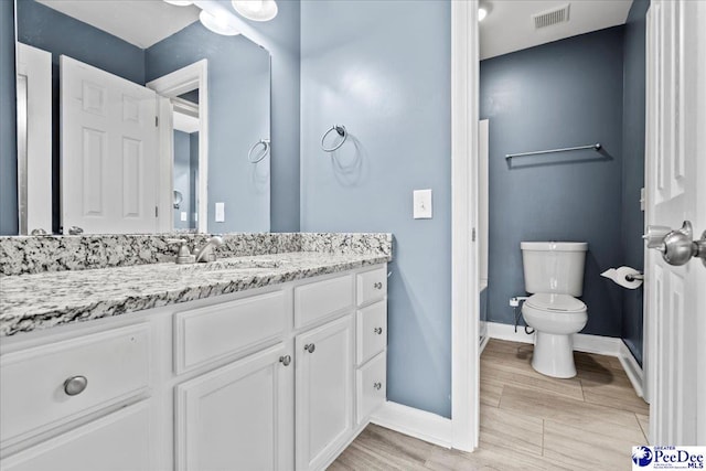 bathroom with visible vents, baseboards, toilet, vanity, and wood finished floors