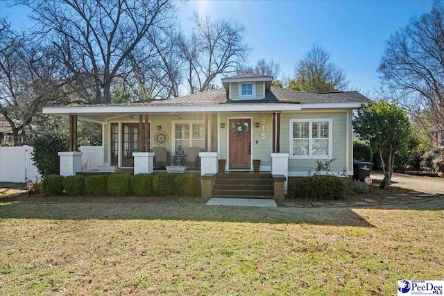 bungalow featuring covered porch, a front yard, and fence