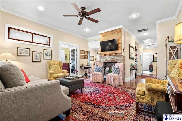 living room with ornamental molding, a fireplace, wood finished floors, and visible vents