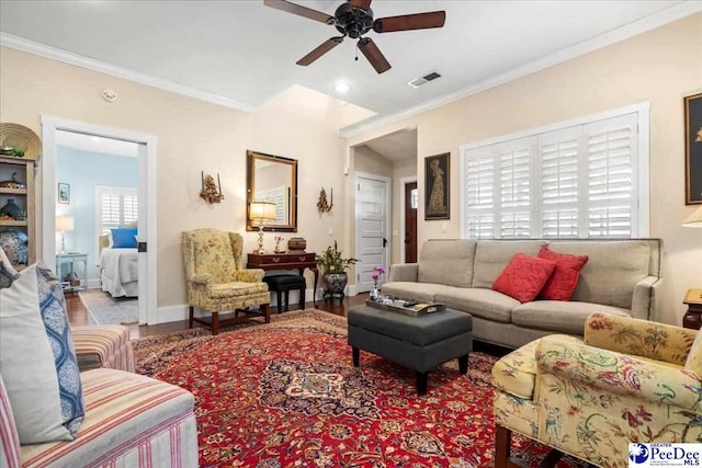 living room with visible vents, ornamental molding, ceiling fan, wood finished floors, and baseboards