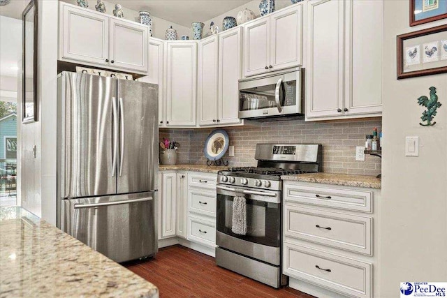 kitchen with appliances with stainless steel finishes, white cabinets, and light stone counters