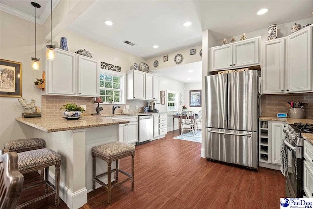 kitchen with visible vents, appliances with stainless steel finishes, white cabinets, a peninsula, and a kitchen breakfast bar