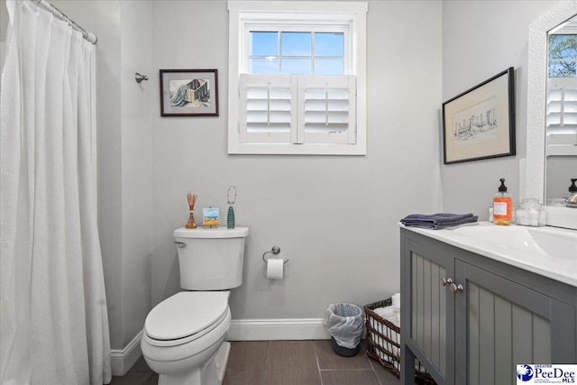 bathroom with toilet, vanity, baseboards, and wood finished floors