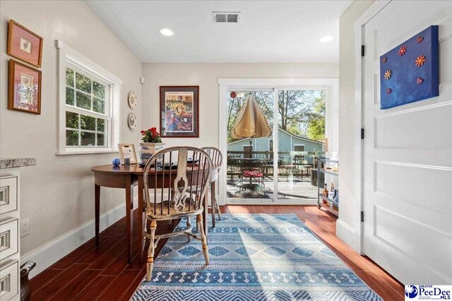 dining room featuring baseboards, wood finished floors, visible vents, and a healthy amount of sunlight