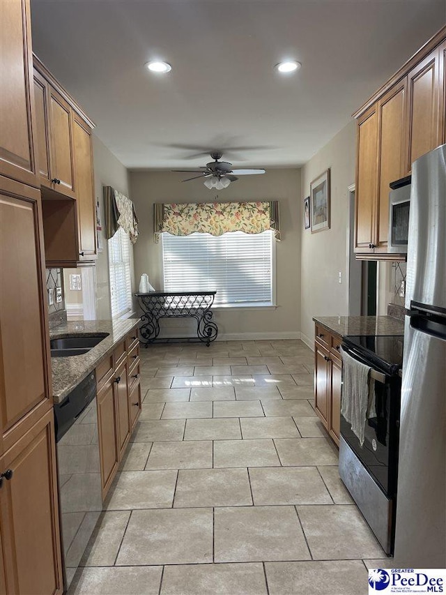 kitchen featuring sink, light tile patterned floors, dark stone countertops, appliances with stainless steel finishes, and ceiling fan