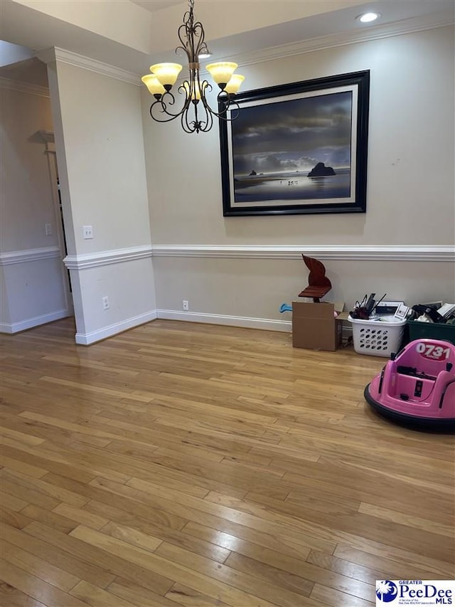 unfurnished dining area featuring ornamental molding, hardwood / wood-style floors, and a chandelier