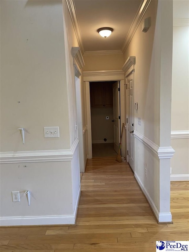 hallway with light hardwood / wood-style flooring and ornamental molding