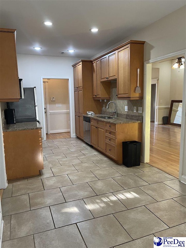 kitchen featuring tasteful backsplash, stainless steel dishwasher, sink, and dark stone countertops