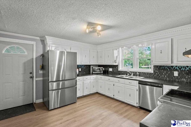 1111 Syracuse St, Darlington, SC 29532 - kitchen featuring appliances with stainless steel finishes, light wood finished floors, ornamental molding, white cabinetry, and tasteful backsplash