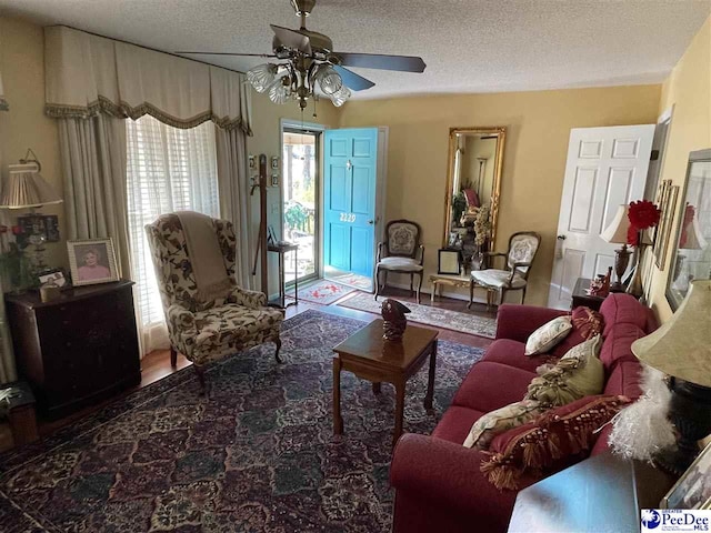 living room featuring ceiling fan and a textured ceiling