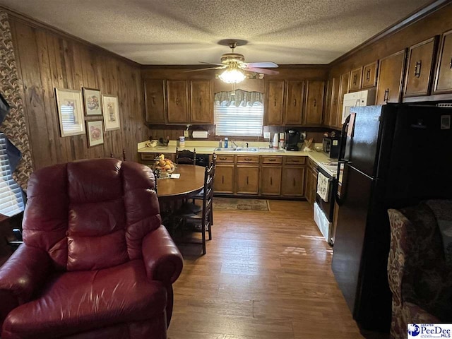 kitchen featuring white electric stove, black refrigerator, a textured ceiling, and light wood-type flooring