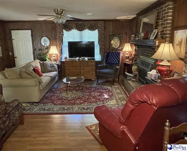 living room with wooden walls, a fireplace, and hardwood / wood-style floors