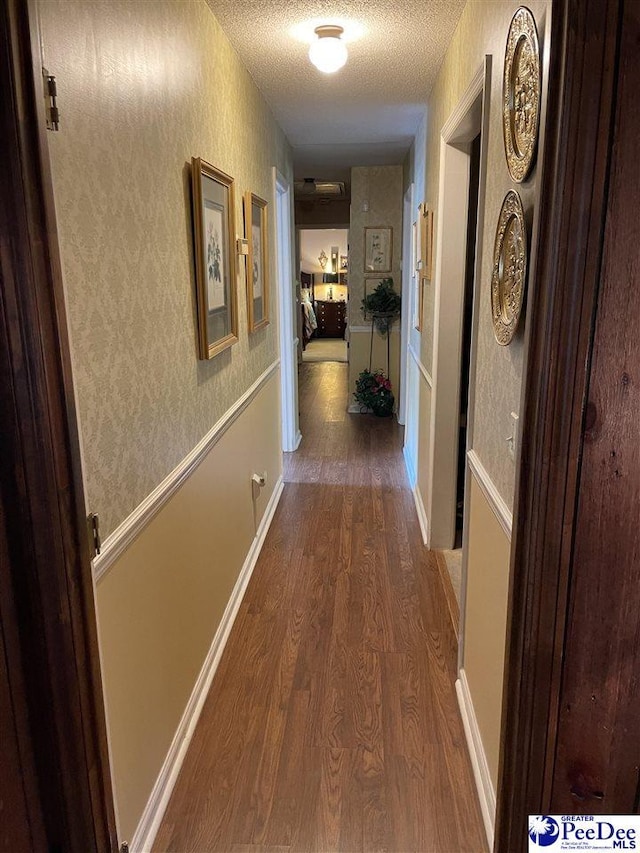 hallway with wood-type flooring and a textured ceiling