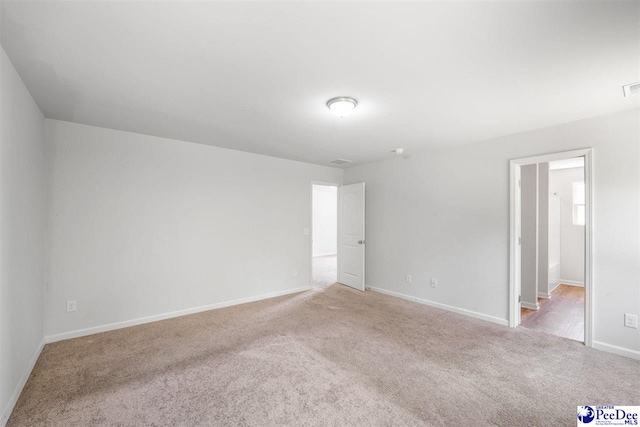 carpeted spare room featuring baseboards and visible vents