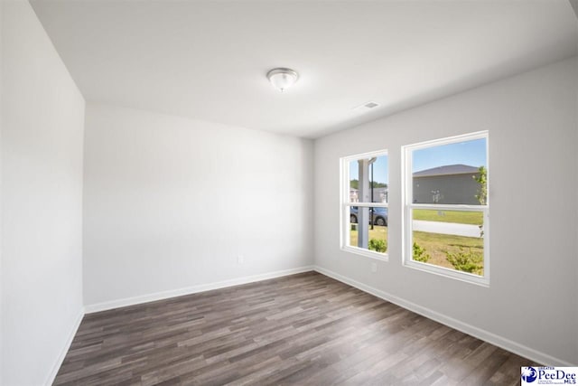 spare room featuring baseboards and dark wood-style floors