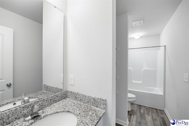 bathroom with wood finished floors, vanity, baseboards, toilet, and bathing tub / shower combination