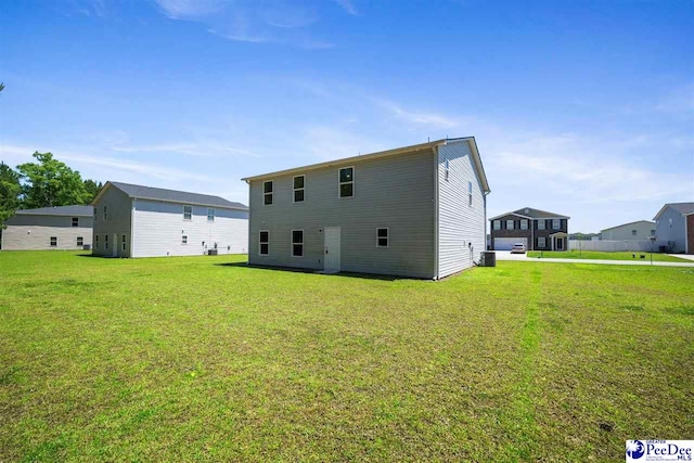 rear view of property with central AC unit and a yard