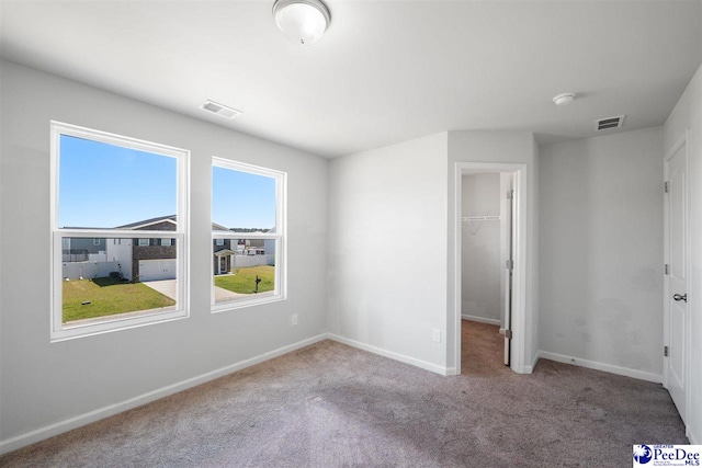 unfurnished bedroom featuring visible vents, baseboards, a closet, a spacious closet, and carpet flooring