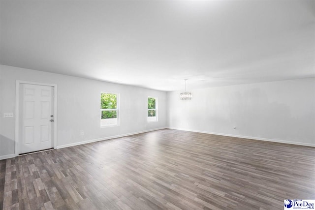 spare room featuring baseboards, a chandelier, and wood finished floors