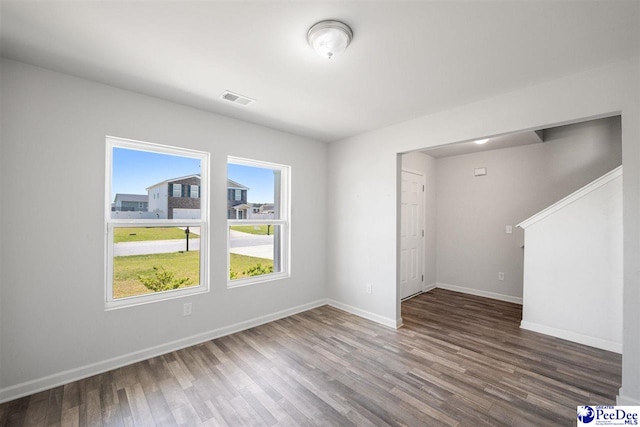 spare room with baseboards, wood finished floors, and visible vents