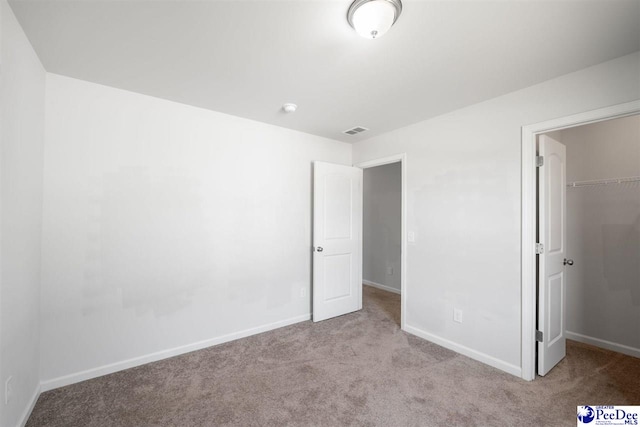unfurnished bedroom with carpet floors, baseboards, a spacious closet, visible vents, and a closet
