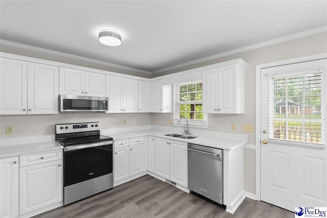 2348 Chadwick Dr, Florence, SC 29501 - kitchen featuring appliances with stainless steel finishes, ornamental molding, light countertops, white cabinetry, and wood finished floors