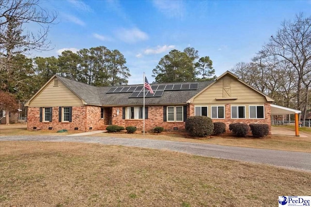 single story home featuring a carport, a front yard, and solar panels