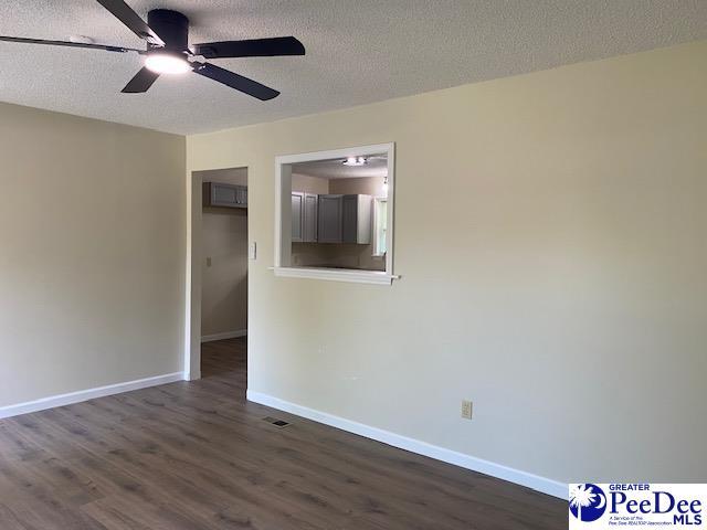 unfurnished room with ceiling fan, dark hardwood / wood-style flooring, and a textured ceiling